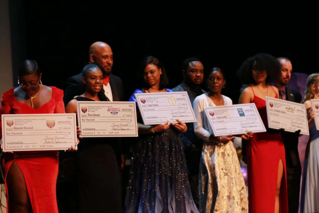 People holding large checks on stage.