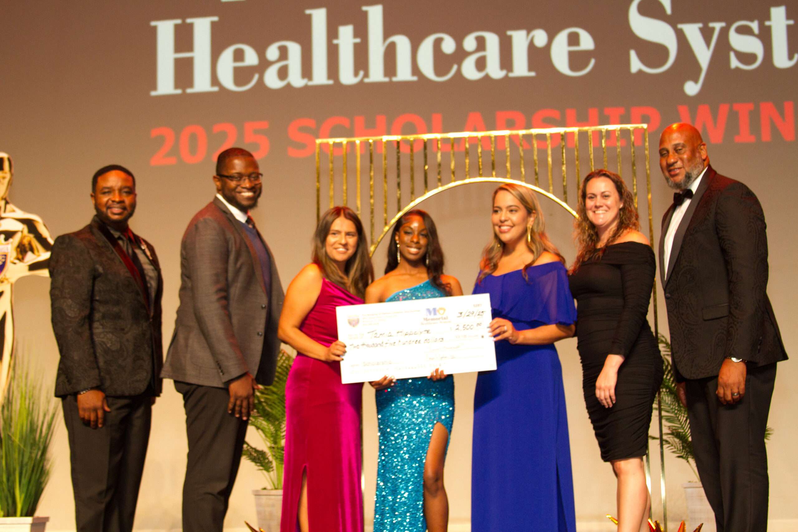 Group of people celebrating a scholarship award on stage.